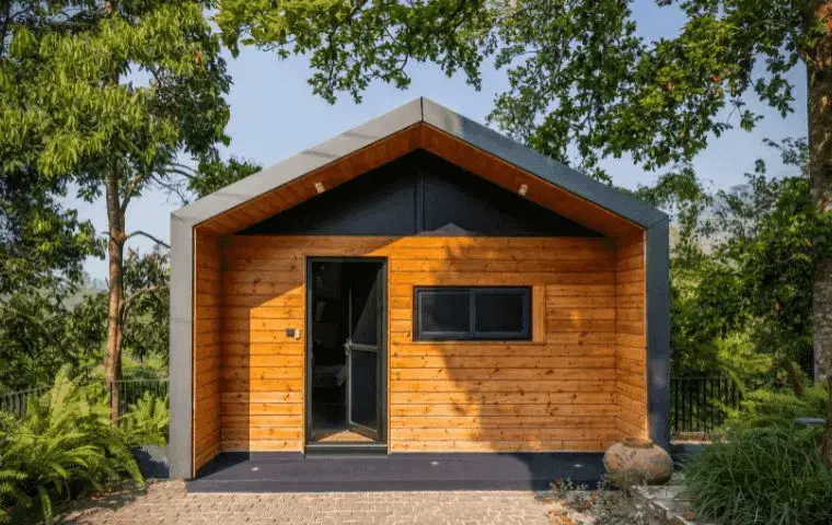 cabaña de madera con cubierta metálica entre árboles